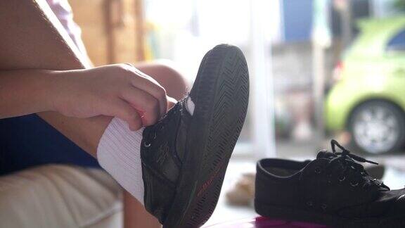 亚洲男生穿着校服穿着袜子、鞋子和紧鞋带在家里与阳光在早上生活理念