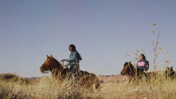 慢动作拍摄的三个美国土著年轻人骑在他们的马在亚利桑那沙漠在一个晴朗明亮的日子