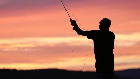 飞钓渔夫在日落湖上的剪影