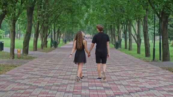 一对年轻夫妇一个男孩和一个女孩在公园的小巷里跑步拥抱嬉戏互相表达感情