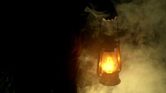 一个男人在晚上拿着一盏煤油灯