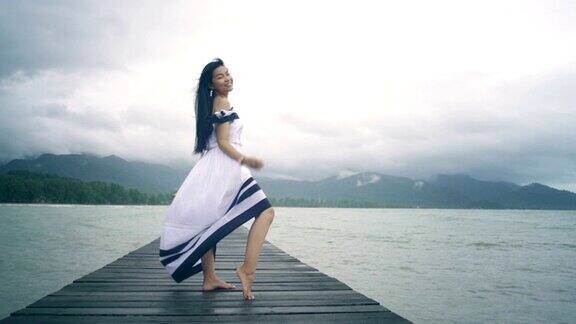 泰国女孩与长头发在白色连衣裙在木制码头