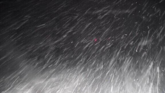 一辆汽车在高速公路上通过雪和暴风雪看透过挡风玻璃落下的雪夜路POV