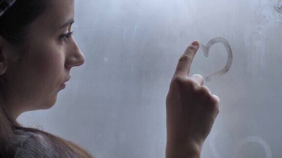 一个年轻女人在窗户上画了颗心