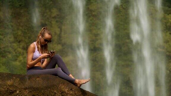 金发女孩赤脚坐在石头上听音乐