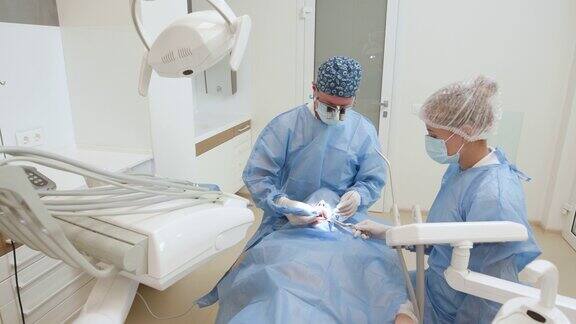 现代牙科医院由两名专业的牙科医生为病人进行口腔植入手术外科手术口腔学治疗概念牙科