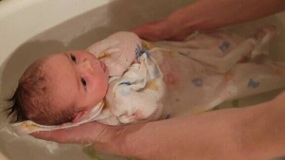 男人的手在浴室里抱着婴儿用布洗新生儿