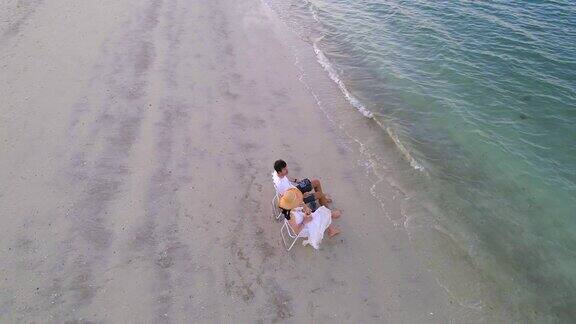 一对情侣在日落时分坐在沙滩上晒黑的椅子上