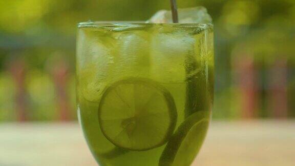 在玻璃杯中搅拌柠檬水热带的背景关闭了酸橙旋转