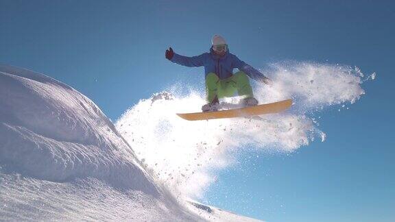 慢动作:专业滑雪板运动员在新雪中跳跃向太阳喷洒雪花