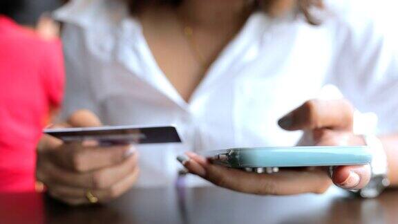 亚洲女性在购物中心手持信用卡使用智能手机