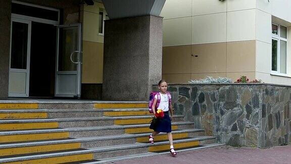 女孩从学校门口拿着背包和花束走下楼梯回到学校夏日握拍女孩拿着一束花走在学校的背景上