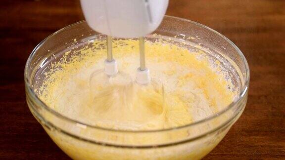 往面团里加面粉用电动搅拌机在碗里搅拌面团特写镜头