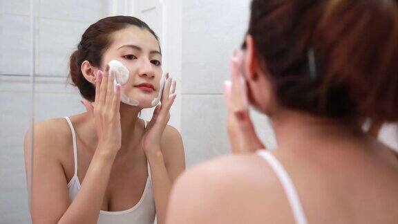 亚洲女人快乐清洁皮肤泡沫在浴室