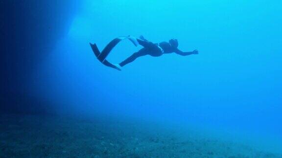 一名潜水员从洞穴里游出来的慢动作水下镜头