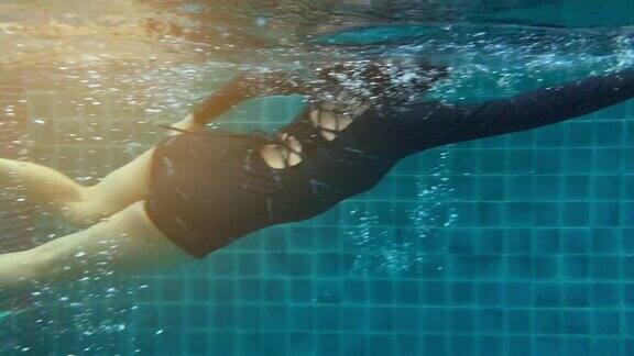 在水景下女子在酒店游泳池游泳的慢镜头