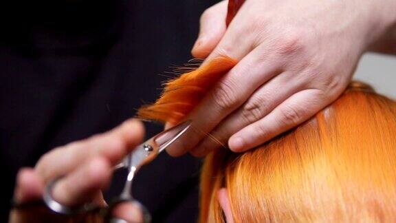 近距离观看红发女人的头发正在被一个专业的发型师在美容院剪男性手握发丝用剪刀和梳子剪Slowmotion拍摄