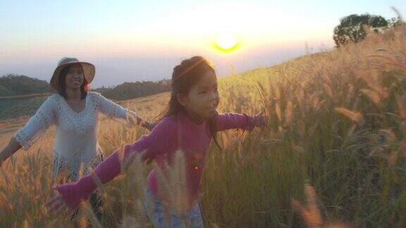 日落时分女孩和母亲跑过草地