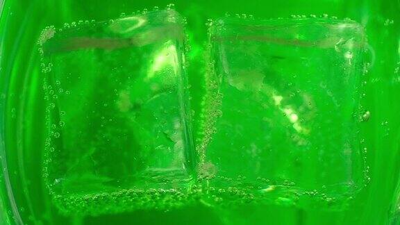 微距摄影方块冰块漂浮在玻璃和绿色碳酸鸡尾酒