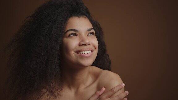 裸体快乐的非洲裔美国妇女触摸她的完美皮肤的脸和肩膀