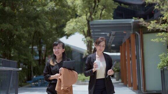 两个女商人在一座现代化的办公大楼里边走边聊