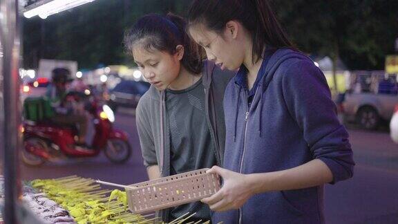 年轻的亚洲女孩选择在夜市烤生鱿鱼泰国街头小吃