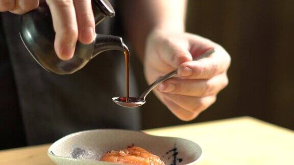 在餐厅的厨房里厨师将日本酱汁倒进装有日本食物的碗里