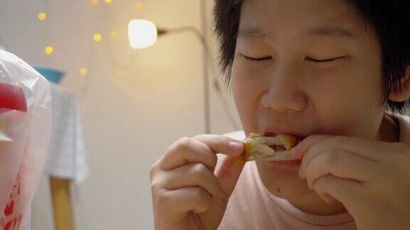 亚洲男孩晚上在家的时候吃烤鸡翅生活理念