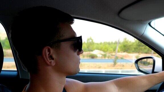 夏日里一个戴着墨镜的帅哥开车穿过乡间小路男人的侧面仔细看着交通和控制他的车辆公路旅行从车里看
