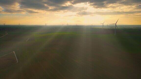 在浓雾中日出的风力涡轮机风力发电场产生绿色能源