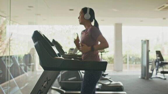 年轻女子在健身房的跑步机上锻炼