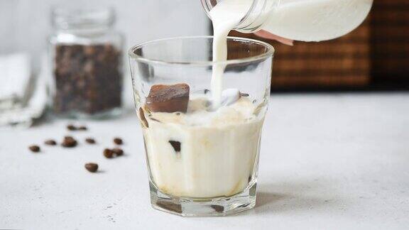 慢镜头将牛奶倒入加冰的咖啡杯中