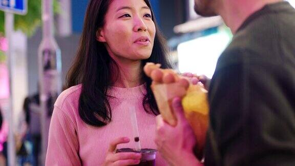 SLOMO手持近距离拍摄一对年轻夫妇在香港吃传统街头小吃