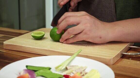 特写镜头中一名男子正在厨房砧板上用金属刀切多汁的青柠