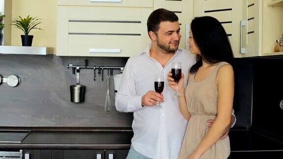 年轻夫妇在家里的厨房里喝红酒