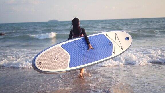 穿着泳衣在海滩上玩冲浪板穿着比基尼的年轻女孩在海滩上玩冲浪板