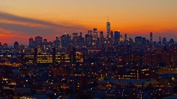 鸟儿在曼哈顿下城的壮观天空中飞翔自由塔在夜晚灯火通明日落时俯瞰布鲁克林住宅区的远景用静态摄像机拍摄的航拍画面