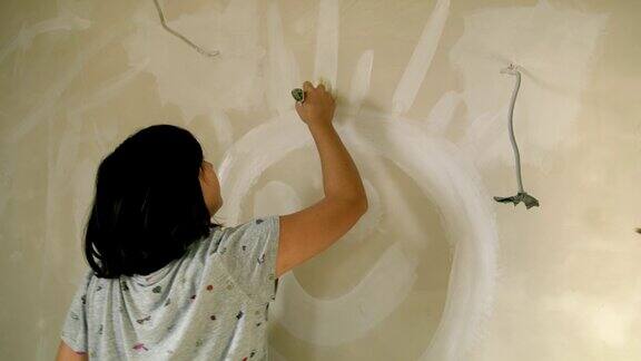 女人用白漆在墙上画笑脸太阳慢动作