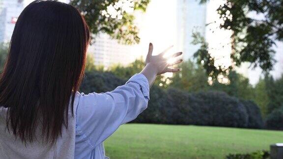 4K:美丽的亚洲女人在中国上海公园触摸太阳耀斑