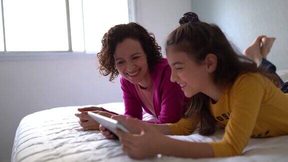 母亲和女儿在家里使用数字平板电脑