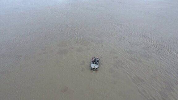 空中跟踪拍摄一艘载着乘客和摩托车横渡湄公河的小渡船
