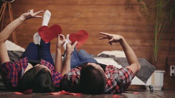 情人节这天一对相爱的情侣在床上玩手工制作的心形玩具