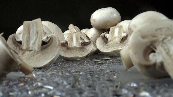 蘑菇切片拍摄在潮湿的黑色反光光滑表面特写