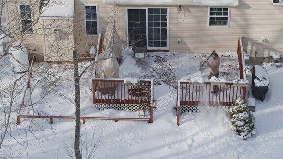 一个成年人在冬天下雪后用铲子清理门廊上的积雪鸟瞰图直接在无人机视频上方