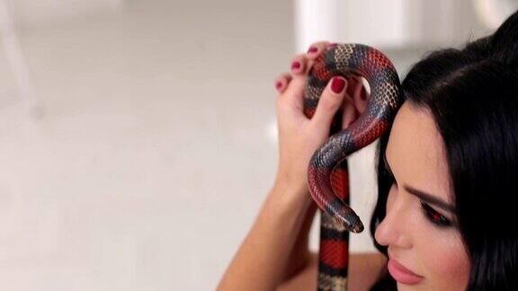 一个化妆的女孩的特写镜头她手里拿着一条蛇