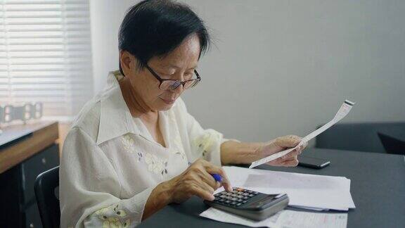 亚洲资深女性每月计算开支支票收据支付