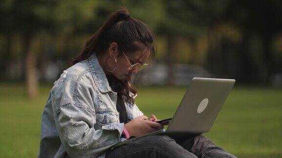 一个女大学生在校园里使用笔记本电脑
