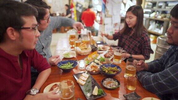 一群亚洲工薪族在日本居酒屋用食物和啤酒吃饭欢呼
