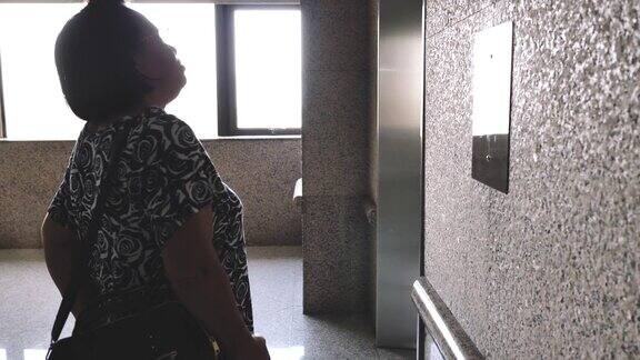 年长的女人在等电梯然后进去