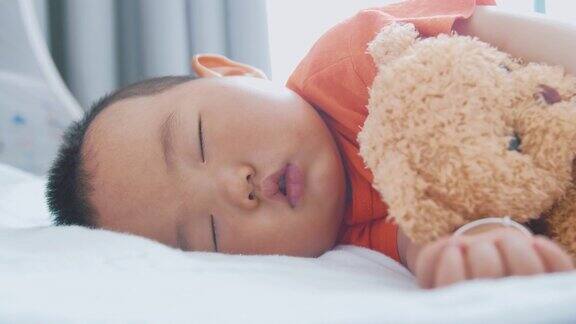 亚洲小男孩和泰迪熊睡觉